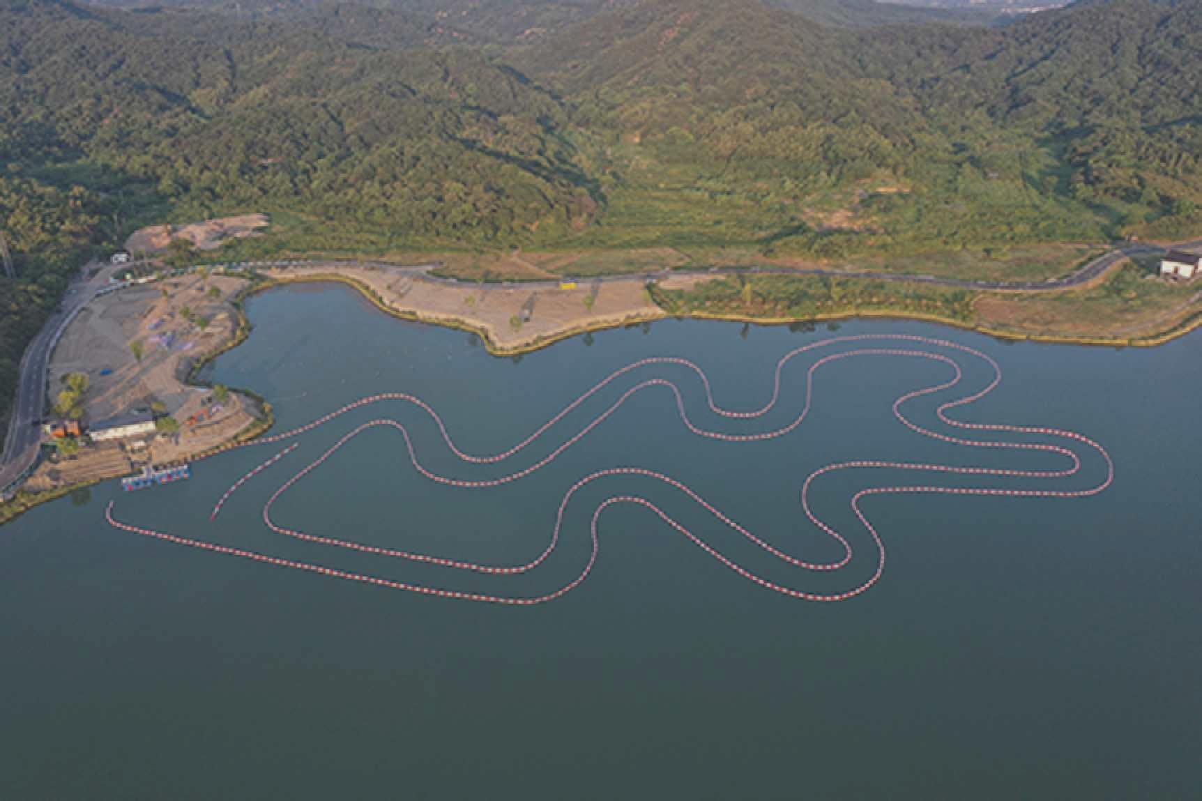 Aerial view of a buoy-marked kart boat track winding across a mountain lake